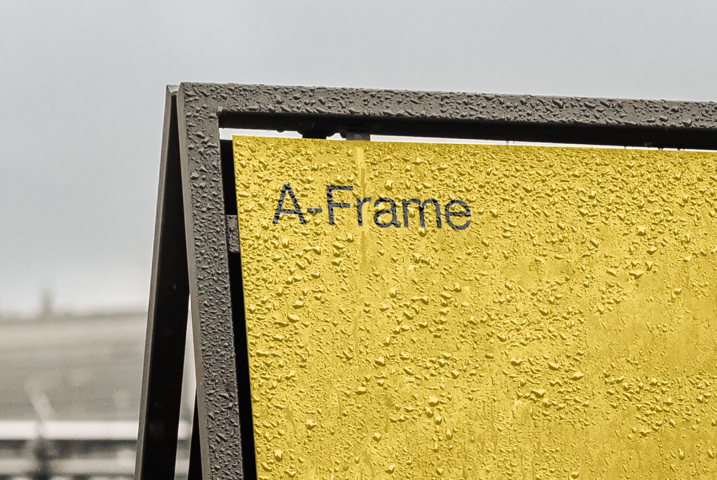 Close-up view of a textured yellow A-frame sign with crisp font, ideal for mockup designs, showcasing graphics or advertising templates.